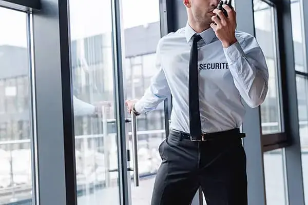 Agent de sécurité patrouillant dans un immeuble de bureaux avec un talkie-walkie